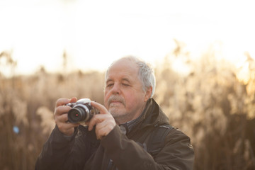 Senior man taking a picture in huge forest by digital camera dur