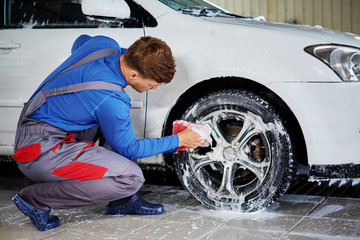 Man worker washing car's alloy rims on a car wash
