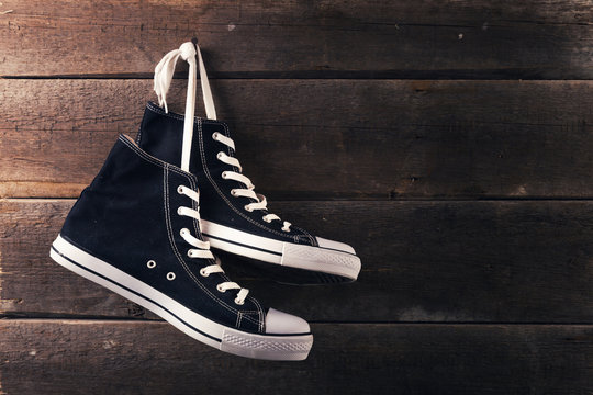 pair of sneakers hang on a nail on a old wooden plank background