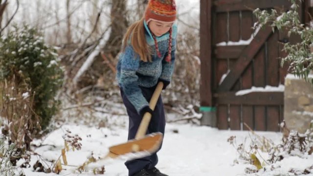Boy removes snow shovel near the house.The child cleans shovel the snow covered track. 
