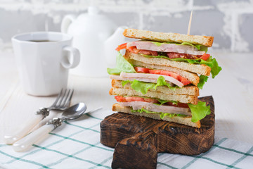 Sandwich for breakfast with stuffed tomatoes with ham and lettuce on a light wooden background. Selective focus.