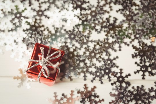 Small wrapped gift box and snowflake scattered on wooden table
