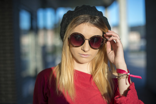 Young woman in glasses and a hat on the street.