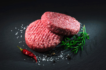 Raw beef hamburger patties with spices - obrazy, fototapety, plakaty