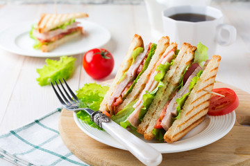 Sandwich for breakfast with stuffed tomatoes with ham and lettuce on a light wooden background. Selective focus.