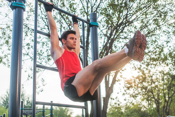 Fitnes man hanging on wall bars performing legs raises. Core cross training working out abs muscles