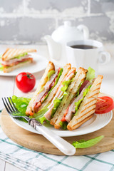 Sandwich for breakfast with stuffed tomatoes with ham and lettuce on a light wooden background. Selective focus.