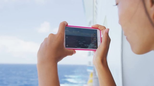 Cruise ship vacation girl taking photo with smart phone camera enjoying travel at sea. Woman using smartphone to take picture of ocean. Woman on luxury cruise liner boat. RED EPIC 96 FPS.
