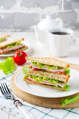 Sandwich for breakfast with stuffed tomatoes with ham and lettuce on a light wooden background. Selective focus.