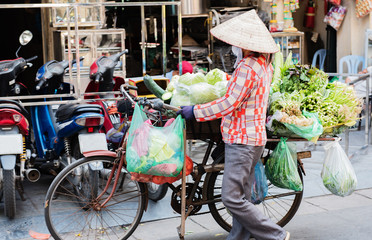 Fototapeta na wymiar vietnamesische alte Frau und Fahrrad mit Obst und Gemüse auf der Straße in Hue, Vietnam 