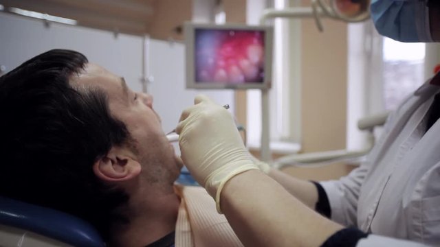 Dentist examining the mouth of a patient with an intraoral camera.