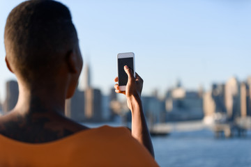African business woman taking picture on the phone outdoor, New York, Manhattan, skyline view, close up