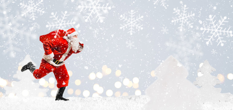 Santa Claus Running At New Year Or Christmas Delivery Rush With Gift Bag Full Of Presents On Snow