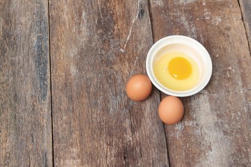 Raw egg in a bowl selective focus on wooden table, Top view 