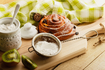 Bun with raisins and sugar powder in the strainer