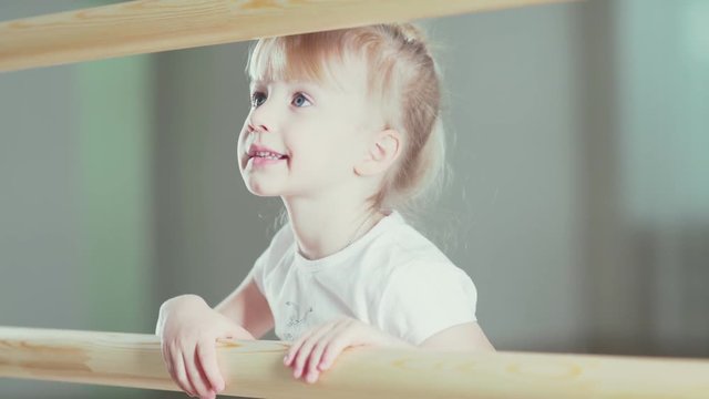 Cute baby is learning to dance near the ballet bar. Children's school of ballet and classical dance. A little girl dreams of becoming a dancer. Ballerina practicing ballet dance at barre in the studio