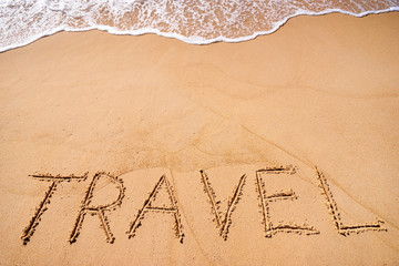 Vacation concept on the beach. Word Travel written on the sand near the sea.