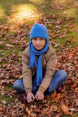 Portrait of smiling boy sitting at park during autumn