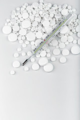 Bunch of white tablets with thermometer. Scattered pills.