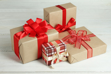 Gifts boxes with red ribbon on a white wooden background.