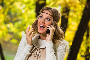 Beautiful boho girl talking on the phone and she is very surprised because of something she hears.
