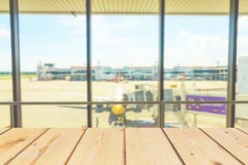 Wooden board empty table in front of blurred background. Perspective brown wood over inside of airport point for looking airplane for mock up  display or montage your products, vintage. 