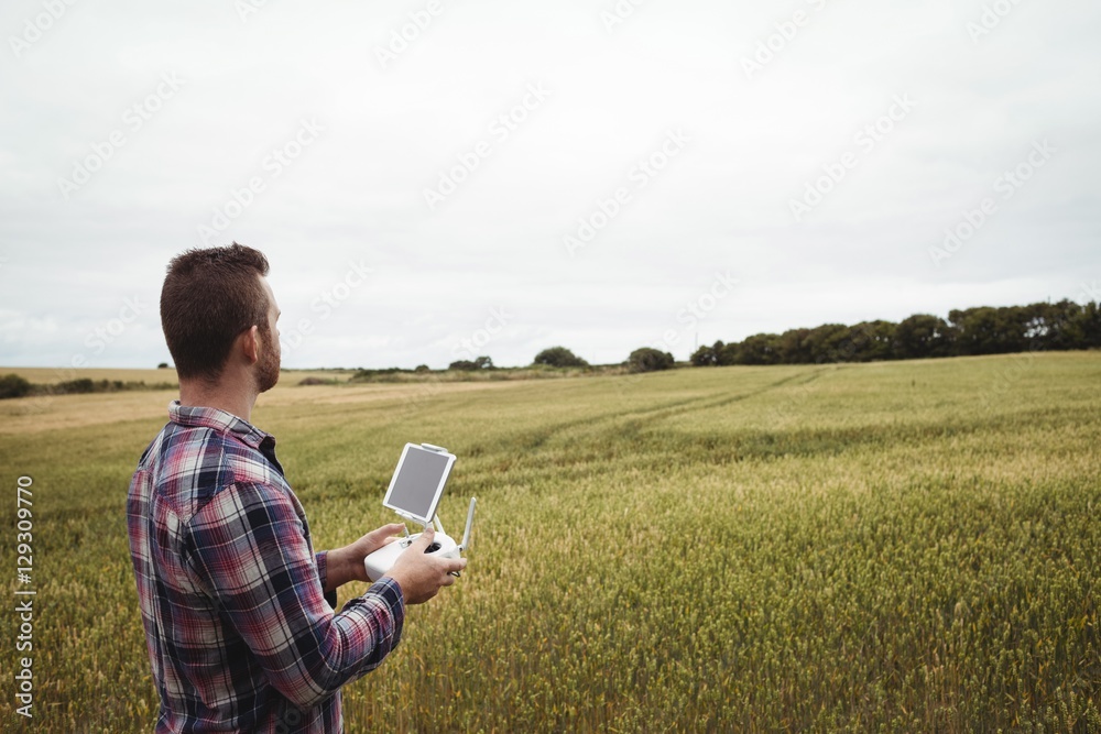 Poster Farmer using agricultural device while examining in field