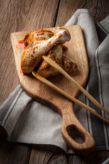 Marinated chicken drumsticks on a wooden chopping board.