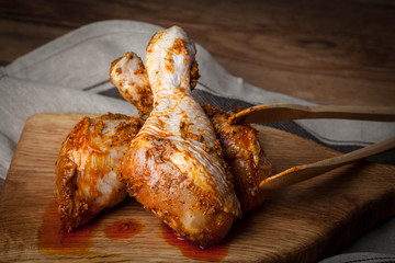 Marinated chicken drumsticks on a wooden chopping board.