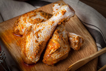 Marinated chicken drumsticks on a wooden chopping board.