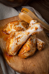 Marinated chicken drumsticks on a wooden chopping board.