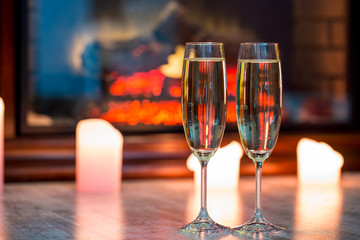 Beautiful two glasses of champagne standing on the table in the background of a blurred room with a decorated Christmas tree and candles. Soft focus. Shallow DOF