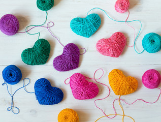 Multicolored Hearts with a balls of thread on white wooden background. Image of Valentines day