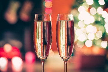 Beautiful two glasses of champagne standing on the table in the background of a blurred room with a decorated Christmas tree and fireplace. Soft focus. Shallow DOF