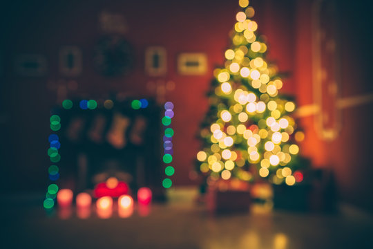 Beautiful  Defocused background new year room with decorated Christmas tree, gifts and fireplace with the glowing lights at night. The idea for postcards. Soft focus. Shallow DOF