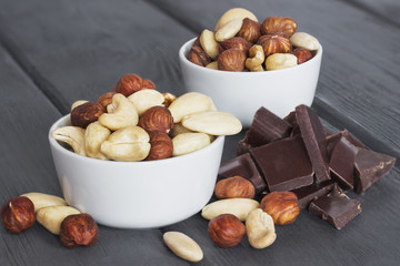 Set of nuts in bowl with chocolate on wooden background - 129312155
