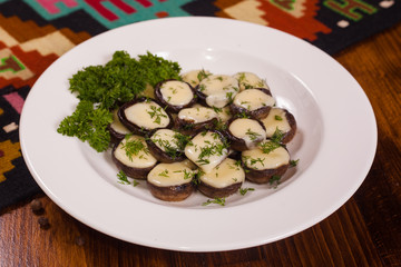 Baked mushrooms with cheese and herbs on a white plate