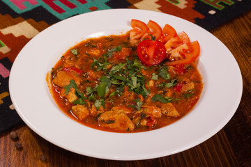 Meat in tomato gravy with fresh herbs in white plate