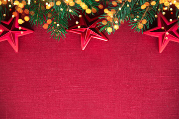Christmas background with xmas tree, red ornaments and glowing golden bokeh lights on red canvas background. Merry christmas card. Winter holiday theme. Happy New Year. Space for text.