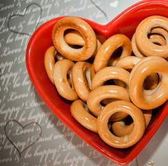 Тop view. Bagels on red plate in shape of heart on gray backgro