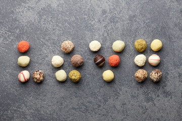 Various chocolate truffle candies arranged in a word love on gray stone background