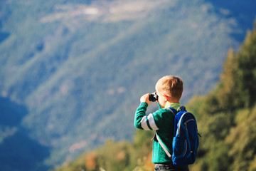 little boy with binoculars hiking in mountains