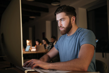 Caucasian bearded businessman working late at night in office