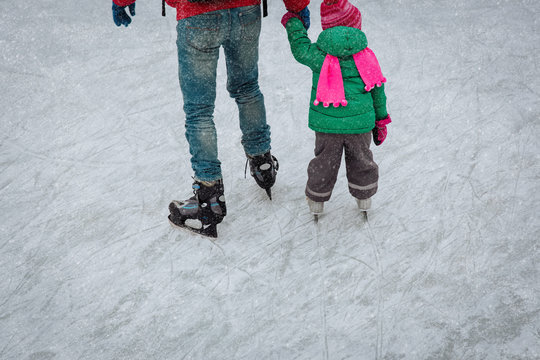 father and little daughter feet learning to skate in winter