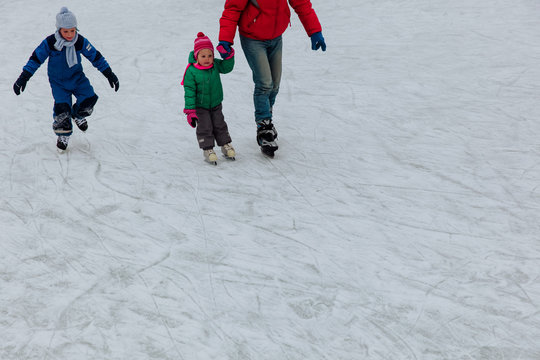 father with two kids skating in winter