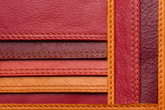 Leather samples with stitches, natural materials with seams of red, maroon, brown, orange colors and other warm shades, woman bag detail, macro shot, selective focus 