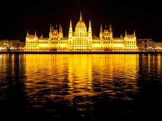 Fototapeta premium Night view of illuminated historical building of Hungarian Parliament, aka Orszaghaz, with typical symmetrical architecture and central dome on Danube River embankment in Budapest, Hungary, Europe. It