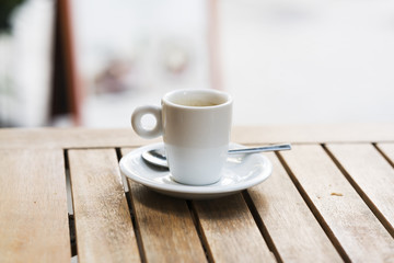 Taza de café con cucharilla sobre una mesa artesanal de madera.