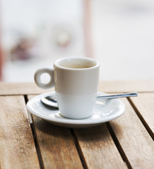 Taza de café con cucharilla sobre una mesa artesanal de madera.