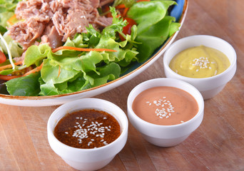 Tuna salad with dressing on wooden background